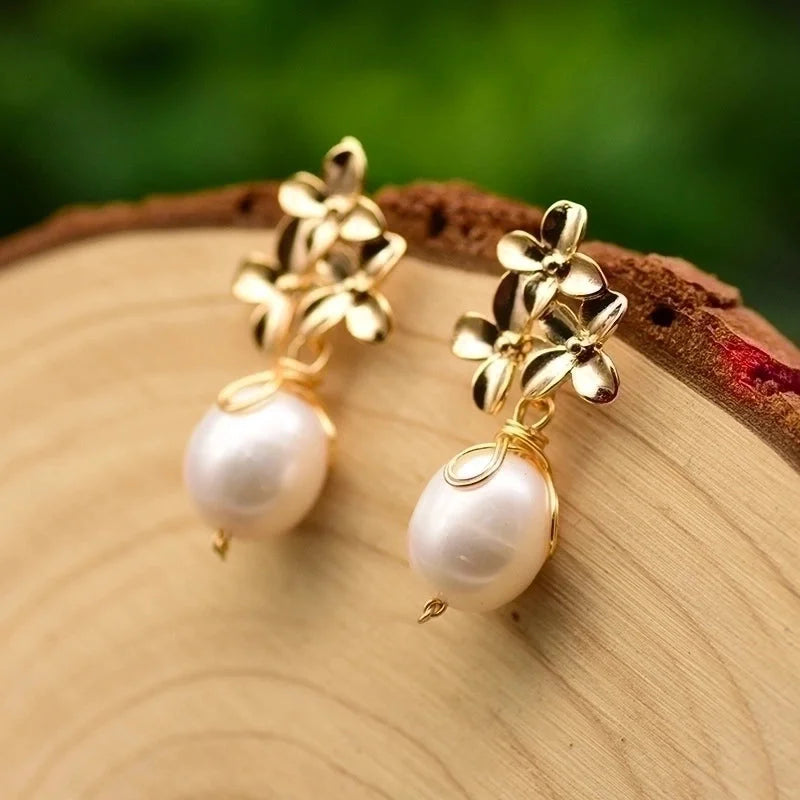Gold earrings with pearl drops on a wooden surface